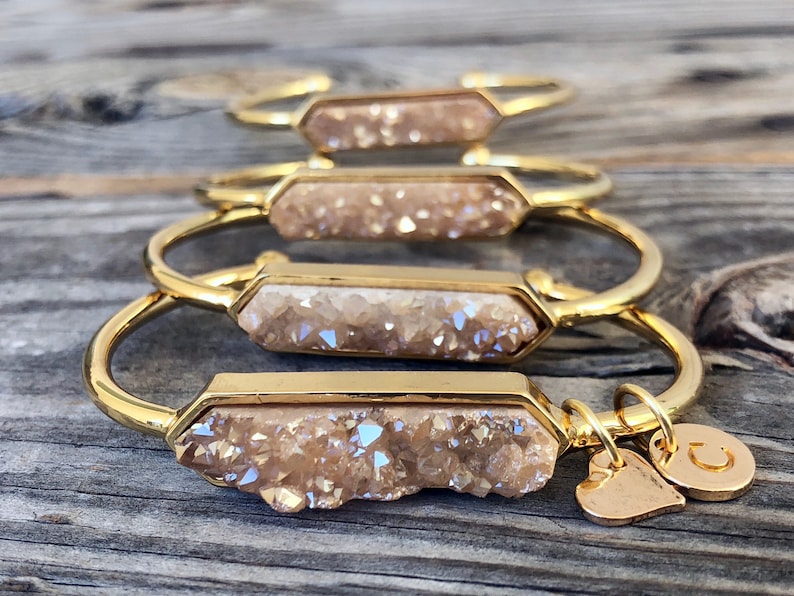 May include: Four gold bracelets with a light brown crystal charm. Each bracelet has a heart charm and a letter charm.