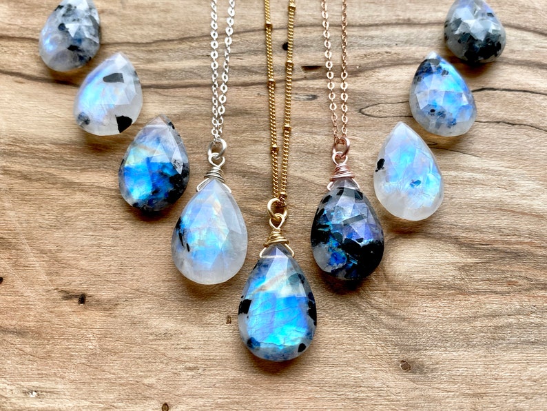 Puede incluir: Tres collares de plata, oro y oro rosa con colgantes de piedra lunar en forma de l&aacute;grima. Las piedras lunares son iridiscentes y tienen un color azul y negro.