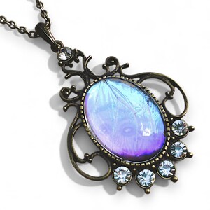A decorative pendant necklace with a large oval-shaped gemstone at the center, surrounded by smaller gemstones and an ornate metal frame.