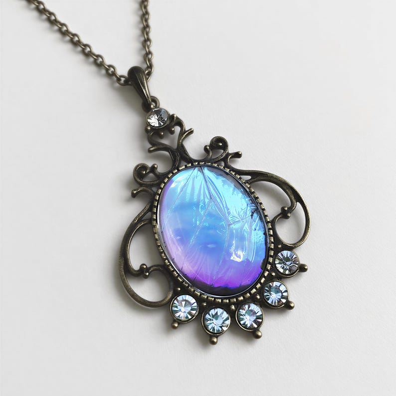 A necklace with a pendant featuring a blue and purple gemstone surrounded by small clear gemstones.