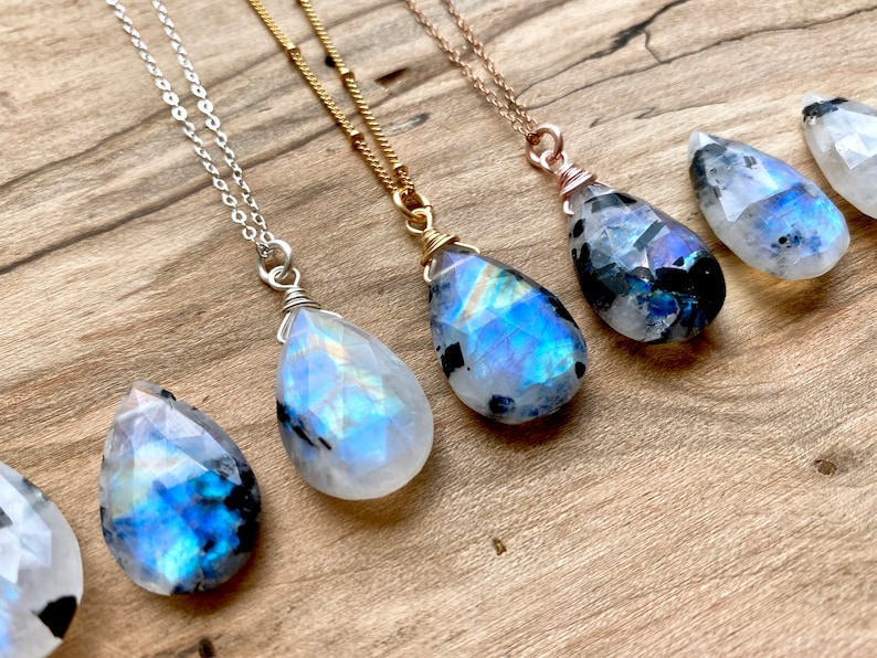 Puede incluir: Cinco colgantes de piedra lunar arco&iacute;ris en forma de l&aacute;grima en cadenas de plata, oro y oro rosa. Los colgantes son de diferentes tama&ntilde;os y tienen una variedad de colores iridiscentes.