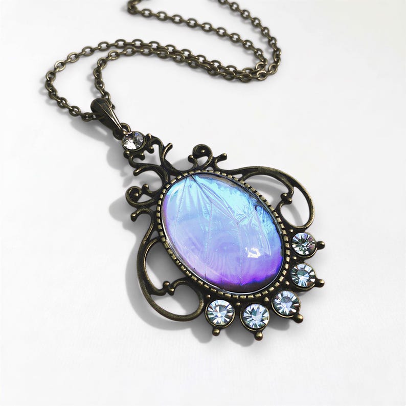 A decorative pendant necklace with a large oval-shaped stone in the center, surrounded by smaller stones and a chain.