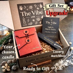 May include: A gift set in a cardboard box with the text "The Vibe Lab" and "Upgrade". The set includes a red envelope-style container, a black matchbox labeled "Handmade Matches", and a card with the text "Light it. Hear it. Feel it."