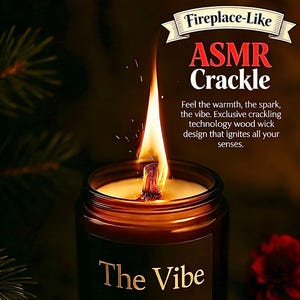 May include: A lit candle in a dark glass jar with the text "The Vibe" in gold lettering. The candle has a wooden wick and the flame is tall and bright. The text "Fireplace-Like ASMR Crackle" is at the top.