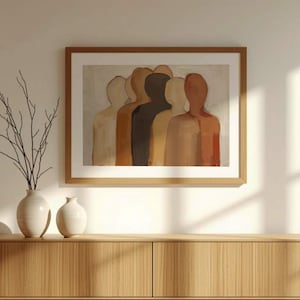 Puede incluir: Una obra de arte enmarcada que representa un grupo de figuras estilizadas en varios tonos de piel. La pintura está en una paleta de colores neutros, con un marco de madera. Dos jarrones blancos y una rama con tallos oscuros están sobre un mueble de madera.