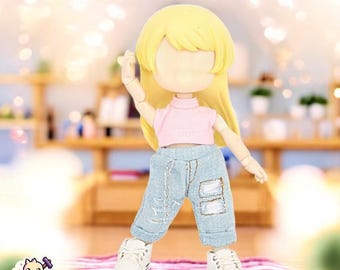 May include: A doll with long blonde hair wearing a pink sleeveless top, blue denim pants, and white sneakers. The doll is standing on a pink and white striped surface.