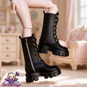 May include: A pair of black mid-calf boots with thick lug soles, silver-toned metal eyelets, black laces, and a vertical silver zipper on the side. The boots are worn on doll legs. A small logo with a cartoon character and the text KawaiiForge is visible.