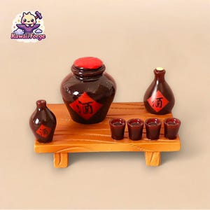 Puede incluir: Un conjunto de mesa de madera en miniatura con una jarra de cerámica marrón, una botella de cerámica marrón más pequeña y cuatro tazas pequeñas rojas. La jarra y la botella tienen etiquetas rojas con el carácter chino para "vino" en ellas.
