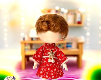 May include: A red and white floral dress with a gold necklace and pearl accents. The doll is wearing white socks and white shoes.