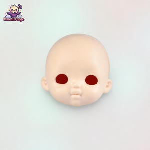 May include: A pale, smooth, bald doll head with a rounded shape, small ears, and a defined nose and mouth. The eye sockets are hollow and dark red, creating a stark contrast against the light skin tone of the face. The surface is matte.