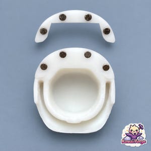 May include: A white, two-piece plastic helmet accessory featuring a circular main section and a separate curved visor piece. Both components are equipped with small, circular metallic magnets embedded at key points for secure attachment.