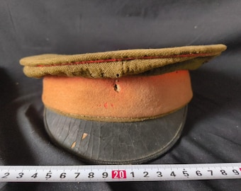 May include: A vintage military style cap with a brown fabric crown, a red and orange felt band, and a black leather brim.