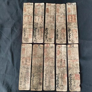 May include: A collection of ten rectangular, aged paper cards with Japanese calligraphy and red seals. The cards have a worn, vintage appearance with visible signs of age and use. The text is in black ink, and the overall color palette is muted.