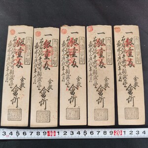 May include: Five antique Japanese paper currency notes. Each note features intricate calligraphy in black ink, red seals, and a rectangular design. A ruler with inch measurements is at the bottom.