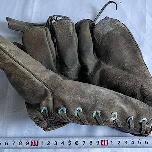 May include: A vintage brown leather baseball mitt with a lace-up closure and metal eyelets. The mitt is worn and has a faded appearance.
