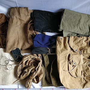 May include: A collection of vintage fabric scraps in various colours and textures, including brown, green, black, and blue. The fabrics are arranged on a white surface and include a large brown canvas bag with multiple pockets.