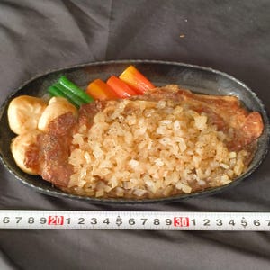 Peut inclure: Un plat de nourriture avec un steak cuit recouvert d'oignons coupés en dés. Le plat est garni de légumes cuits, notamment des haricots verts, des carottes et des champignons. L'assiette est sombre et de forme ovale.