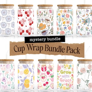 May include: A collection of glass cups with wooden lids and straws, each adorned with unique, colorful designs. The cups feature various patterns, including flowers, cherries, lemons, and whimsical illustrations. The text "mystery bundle" and "Cup Wrap Bundle Pack" are also visible.