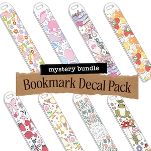 May include: A collection of clear bookmark decals with various designs, including floral patterns, fruit slices, and whimsical illustrations. The text "mystery bundle" and "Bookmark Decal Pack" are displayed on the image.