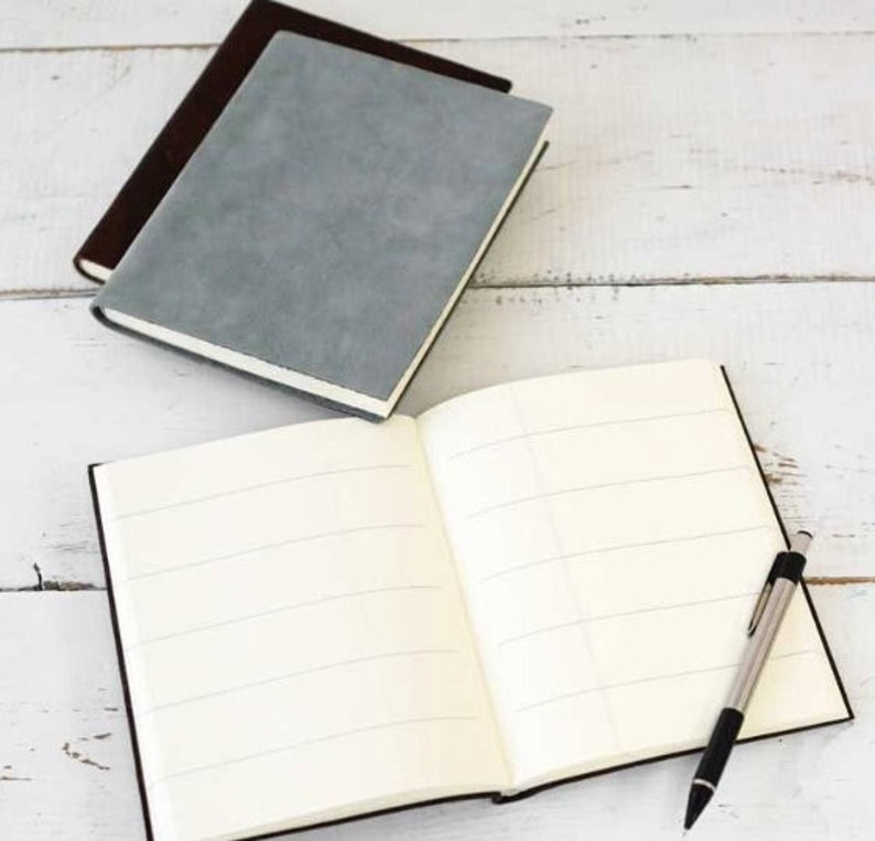 May include: Two gray and brown notebooks with lined pages and a black pen. The notebooks are closed and the pen is lying on top of the open notebook.