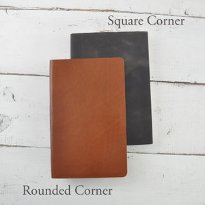 May include: Two leather-bound notebooks, one with rounded corners and one with square corners. The notebook with rounded corners is brown and the notebook with square corners is black.