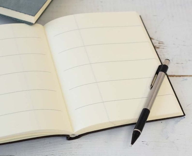 May include: An open notebook with lined pages and a silver mechanical pencil lying on a white wooden surface.