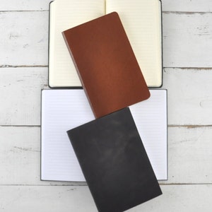 May include: Three notebooks with lined pages. The top notebook is cream colored with brown leather cover. The middle notebook is brown leather with a cream colored cover. The bottom notebook is black leather with a cream colored cover.