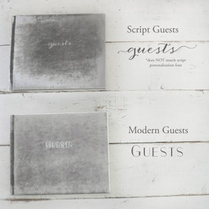 May include: Two gray velvet guest books with different lettering styles. The top book has the word "guests" written in a script font. The bottom book has the word "GUESTS" written in a modern font.