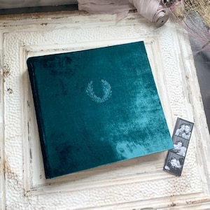 Soft, lush, velvet photo album. Shown here in the 12x12 inch large size, in a rich peacock green color with the laurel leaf stamped in the center.