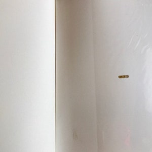 Puede incluir: Un libro blanco en blanco con una encuadernaci&oacute;n y un ligero pliegue en la portada.