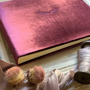 Luxurious, soft, velvet photo album. Shown in the 9x12 inch size, and wine velvet color. Options to personalize with one of our art emblems, or add your own text for additional cost. Wheat emblem shown here debossed in center of cover