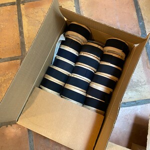 May include: A cardboard box filled with rolls of black and white striped fabric.