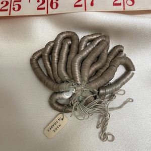 May include: A pile of silver-coloured metal sequins, tied together with string. A small tag reads "MADE IN FRANCE".
