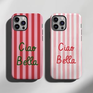 Op de afbeelding: Twee telefoonhoesjes met verticale strepen. Eén hoesje heeft rood-roze strepen met de tekst "Ciao Bella" in groene letters. De andere heeft roze-witte strepen met dezelfde tekst in rode letters.