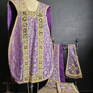 Könnte beinhalten: Ein Satz liturgischer Gewänder in Lila, Gold und Schwarz. Das Set umfasst eine Kasel, Stola, Manipel und Bursa, alle mit kunstvollen Kreuz- und Blumenmustern. Die Gewänder werden auf einer Schaufensterpuppe und einem Stuhl präsentiert.