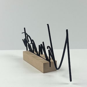 May include: A black metal word art piece that reads "Brand" in a cursive font, mounted on a rectangular wooden base. The word art is a decorative item.
