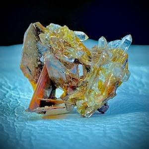 May include: A cluster of golden and clear quartz crystals with a reddish-brown mineral base. The crystals are arranged in a chaotic and organic way, creating a unique and interesting display.