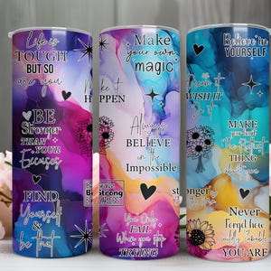 Könnte beinhalten: Drei Edelstahlbecher mit inspirierenden Zitaten und floralen Akzenten. Die Becher haben farbenfrohe abstrakte Hintergründe mit Sätzen wie "Life is Tough But So Are You" und "Believe in Yourself."