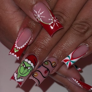May include: Long, square-shaped acrylic nails with Christmas-themed designs. The nails feature red, white, green, and pink colors, with images of snowflakes, the Grinch, and Christmas lights. Some nails have a French tip design.