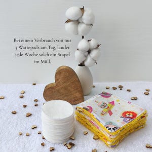Auf diesem Bild steht eine kleine Vase mit Baumwollpflanzen und daneben ein Herz aus Holz. Im Vordergrund liegt das nachhaltige Abschminkpad-Set, alle sieben Pads liegen aufeinander und daneben ein Stapel mit einmal Wattepads. Bei einem Verbrauch von nur 3 Wattepads am Tag, landet jede Woche ein solcher Stapel im Müll. Die wiederverwendbaren Abschminkpads kannst du nach Gebrauch mit deiner regulär anfallenden Wäsche einfach waschen.