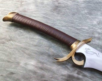 May include: A sword with a curved, dark brown leather-wrapped handle and a metallic gold-toned guard. The blade is silver-colored and features a small, etched outline of a creature near the hilt, which connects to the guard.
