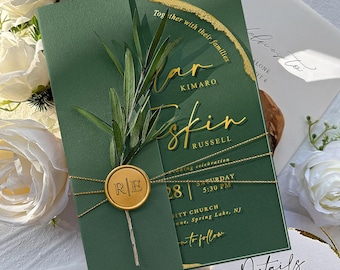 May include: A green wedding invitation with gold accents and text. The invitation is adorned with a sprig of greenery and a gold wax seal. The text includes names, date, time, and location.