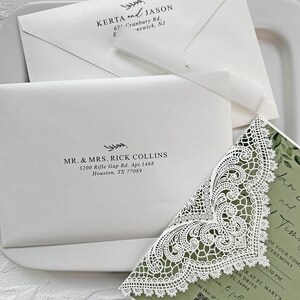 Peut inclure: Un ensemble de faire-part de mariage blanc &eacute;l&eacute;gant, comprenant des enveloppes avec des noms et adresses imprim&eacute;s, et un coin d'invitation d&eacute;coratif d&eacute;coup&eacute; au laser. L'ensemble comprend un ruban et une perle. Le texte comprend des noms, adresses et d&eacute;tails de l'&eacute;v&eacute;nement.