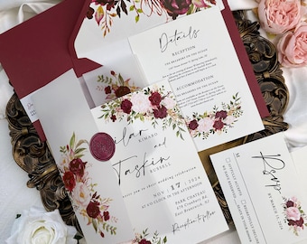 May include: Elegant wedding invitation suite featuring burgundy and blush floral accents. Includes invitation, RSVP card, details card, and envelope. The invitation reads "Ilar and Taskin Russell" and the date "Nov 17 2024".