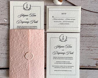 May include: Wedding invitation suite featuring a blush pink envelope with a wax seal, and matching white cards with black text. The invitation includes the names Jihyun Kim and Doyoung Paik, and RSVP information.