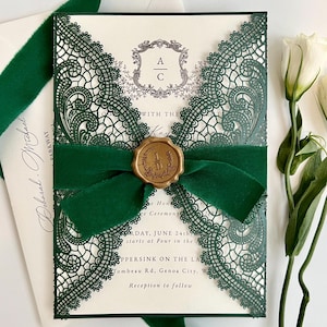 May include: Elegant wedding invitation with intricate green lace detailing. The invitation is tied with a dark green velvet ribbon and sealed with a gold wax stamp. The invitation includes the text "AC" and wedding details.