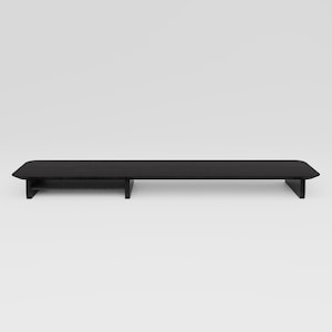May include: Black wooden stand with a shelf for a monitor or other electronics. The stand has a modern design and is made of sturdy wood.