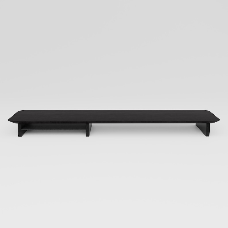 May include: Black wooden stand with a shelf for a monitor or other electronics. The stand has a modern design and is made of sturdy wood.