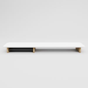 May include: White wooden desk riser with a black shelf underneath. The riser has a long, rectangular shape and is supported by four wooden legs.