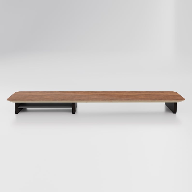 May include: A wooden monitor stand with a shelf for storage. The stand is brown with a dark brown base.